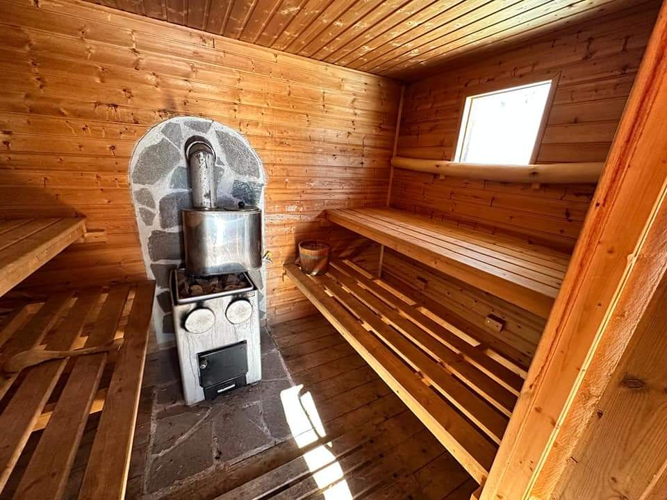 Intérieur en bois du sauna avec ses bancs et son poêle